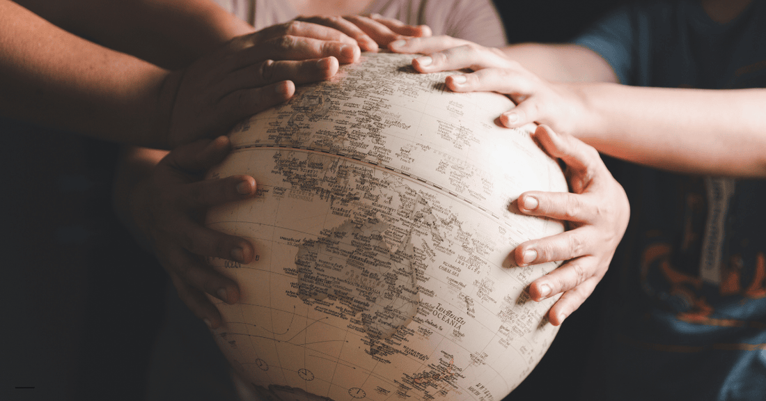 Missionaries praying over a globe as they prepare to spread the Christian gospel.