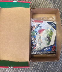 Open cardboard box with a plastic-wrapped toy on a textured carpet