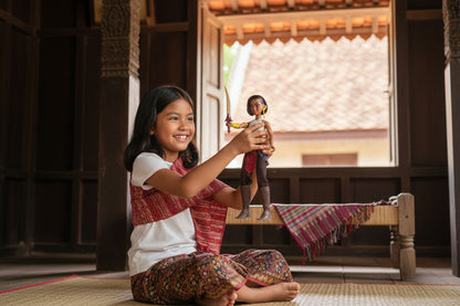 Young girl holding a small figurine in a traditional setting