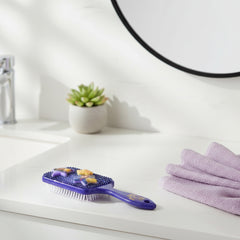 Two Disney-themed hairbrushes laying on a vanity teeth down