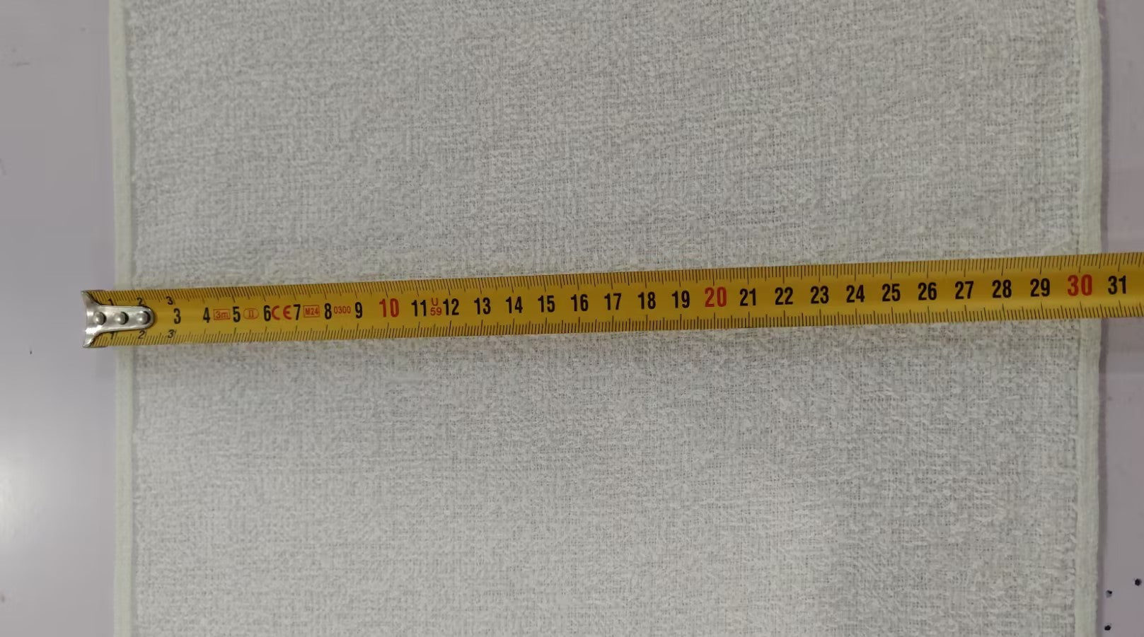 Gray textured fabric with a measuring tape indicating dimensions