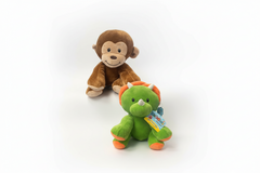 Plush monkey toy held by a hand next to a green dinosaur toy on a white background